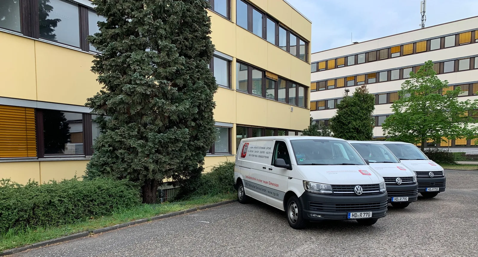 Drei weiße RGS-Servicetransporter auf einem Parkplatz vor Bürogebäuden